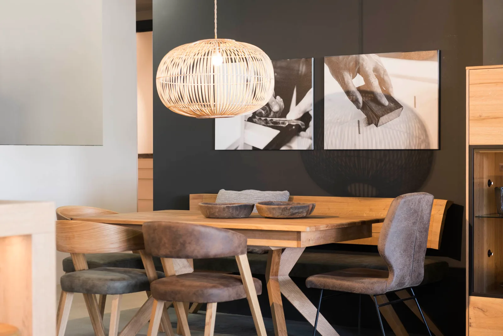 Essplatz im Showroom mit Holztisch, Eckbank, gepolsterten Stühlen und Rattanleuchte